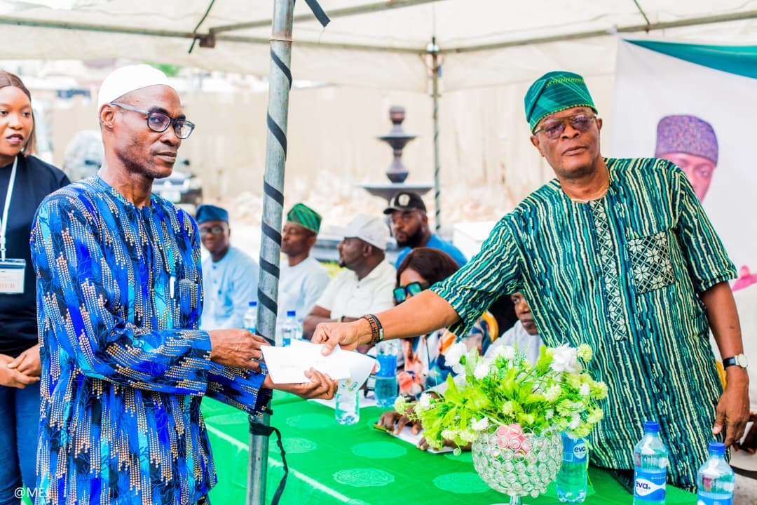 CDA executive handing an envelope to a Kosofe beneficiary